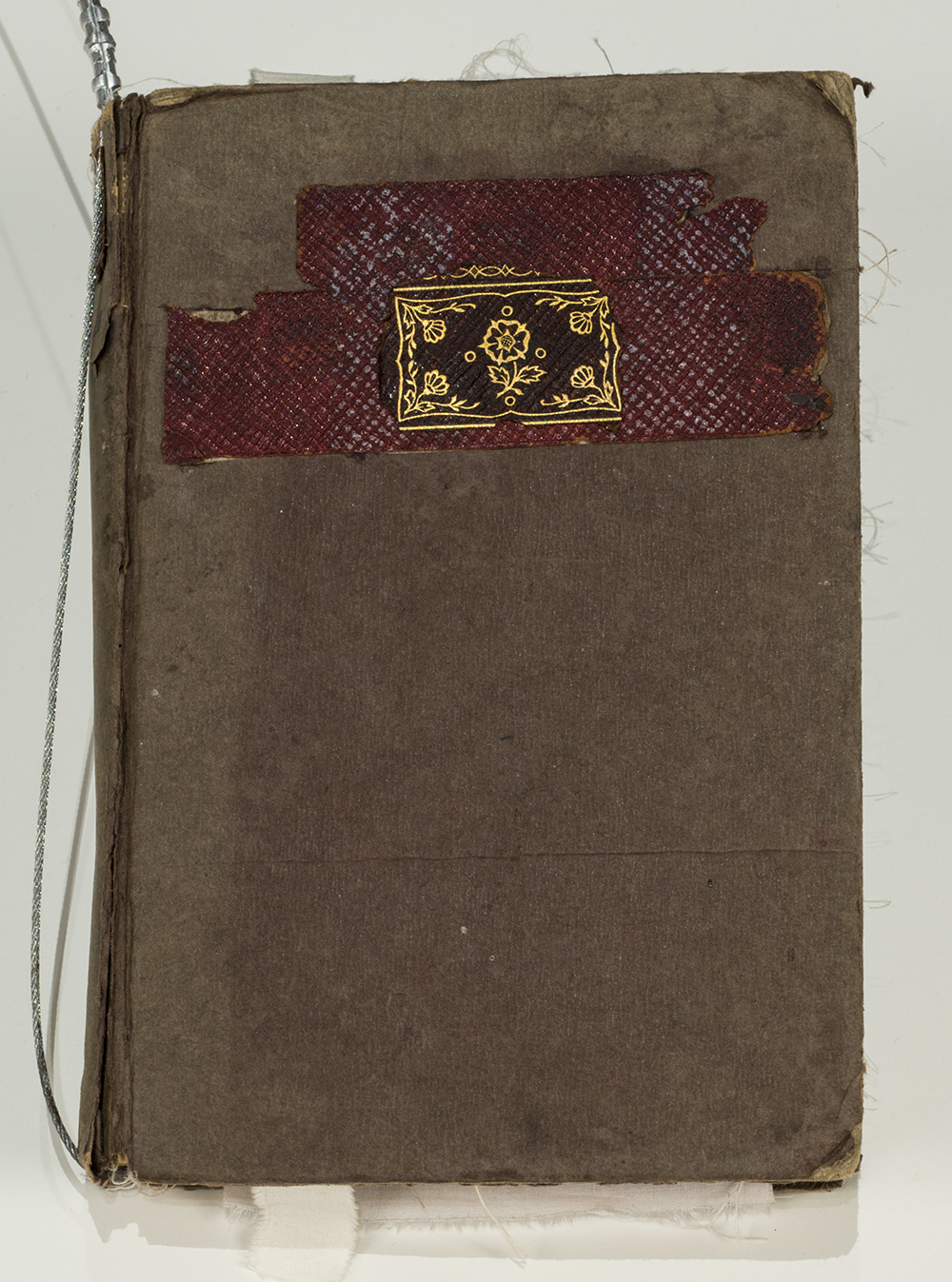 A worn book bound in brown paper with a gold inlay.