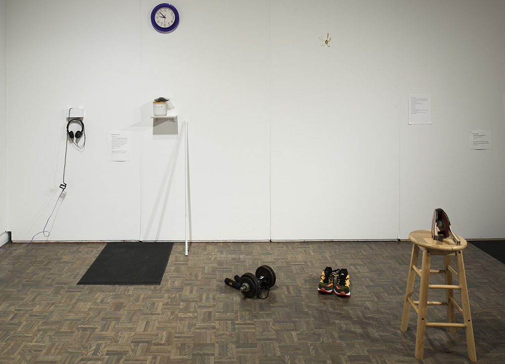 A gallery with a dumbbell, a pair of running shoes, and a stool with ping-pong rackets.