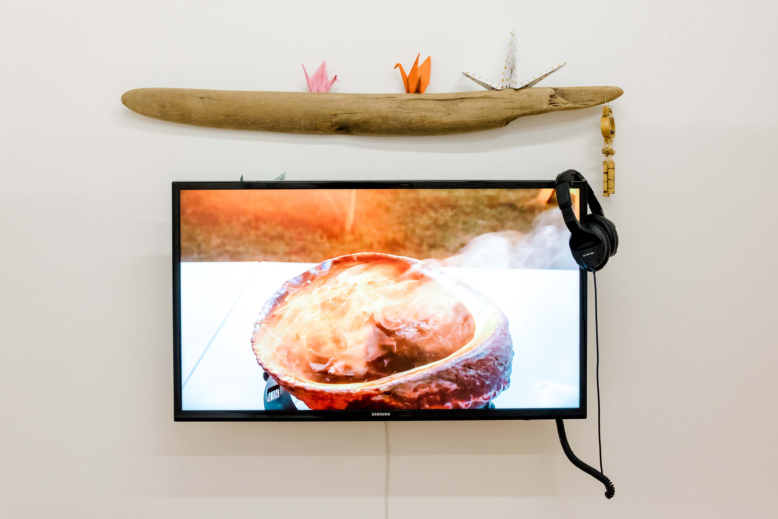A television showing a small fire mounted below a piece of driftwood.