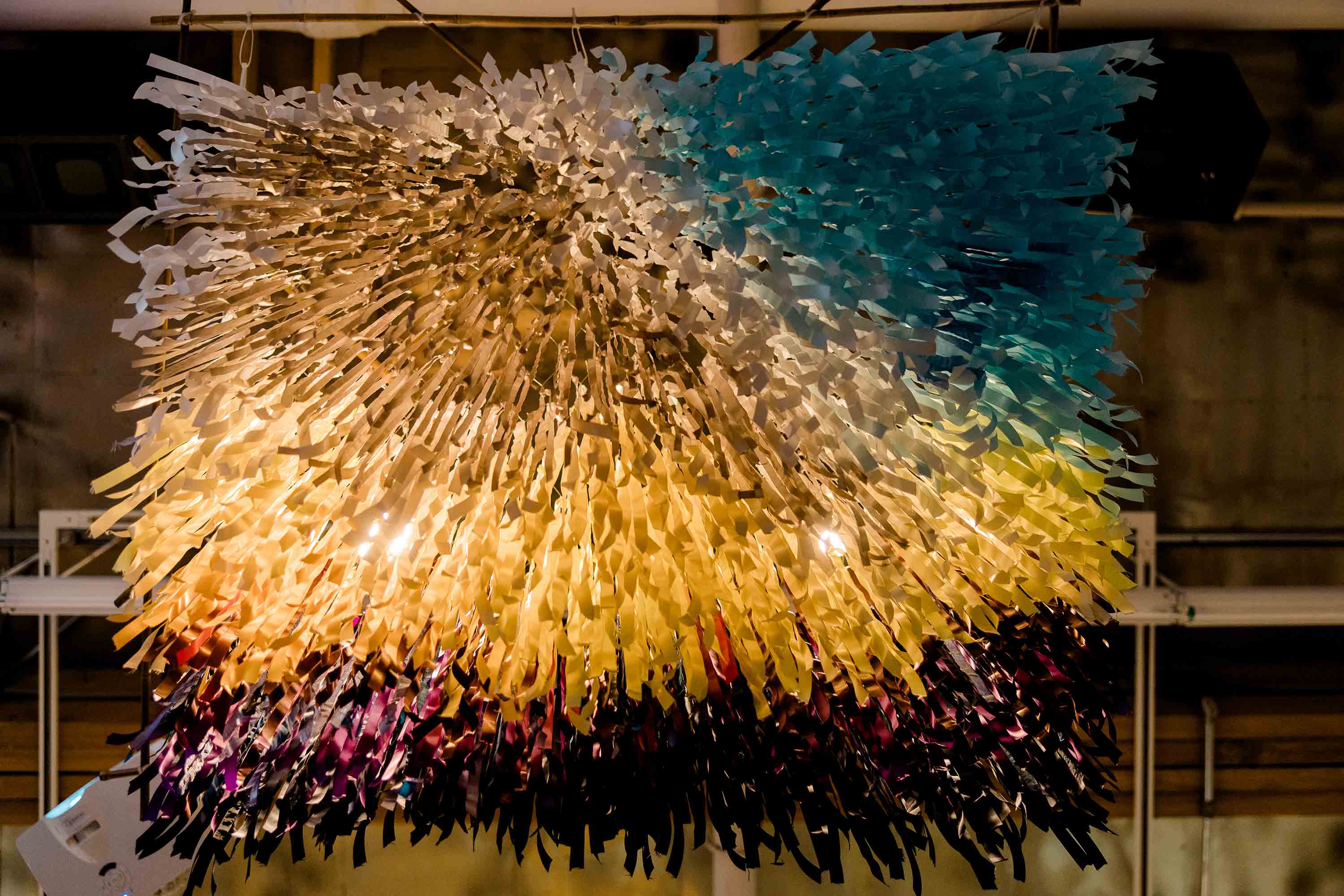 Hundreds of colourful strips of paper hanging from a light fixture.