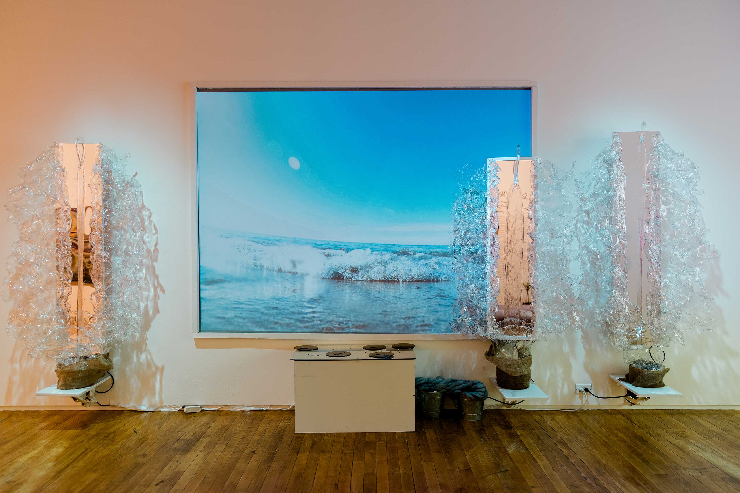 A screen showing a frozen ocean scene, and three sculptures resembling large splashes of water.