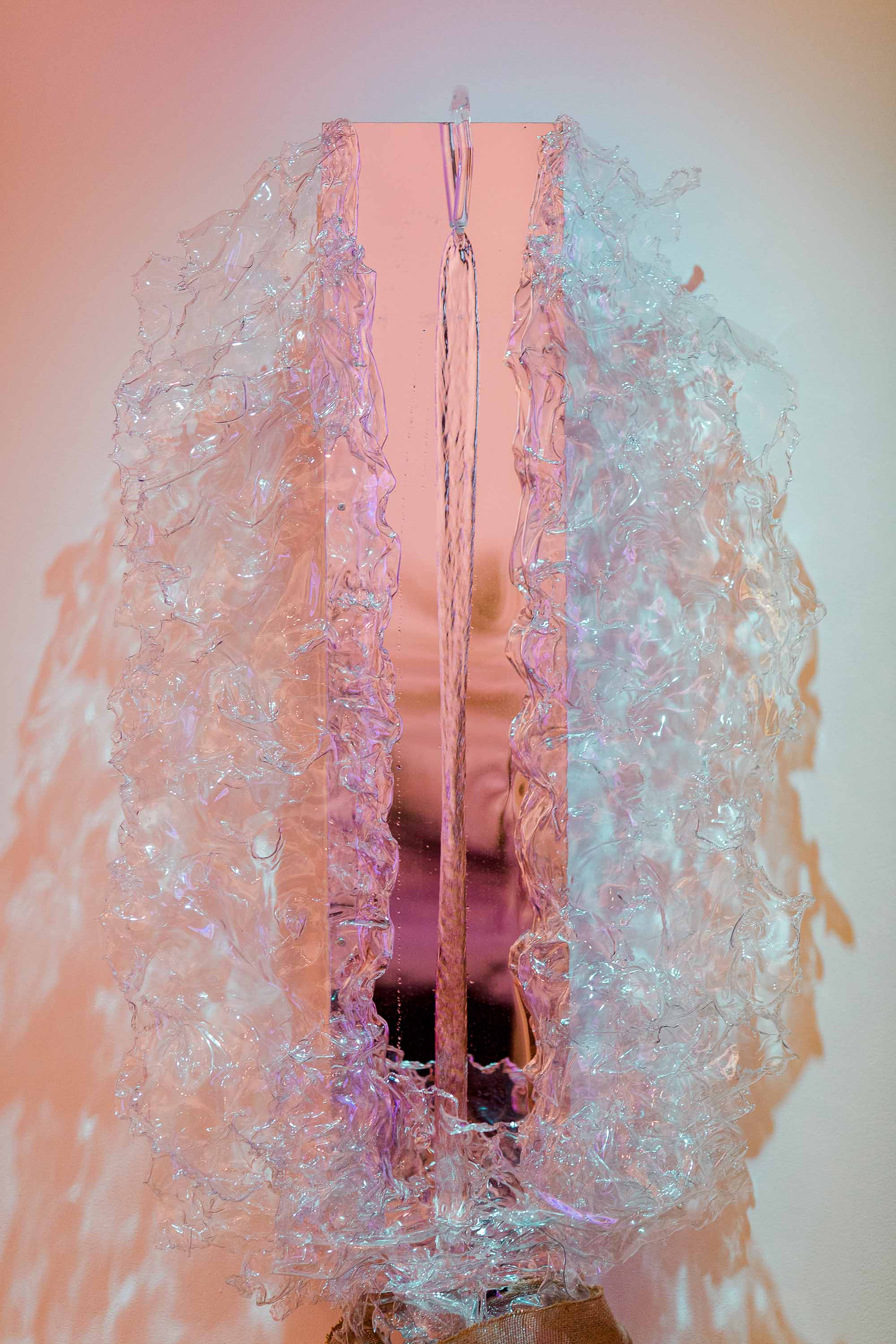 A sculpture resembling a splash of water around a mirror, with water flowing through.
