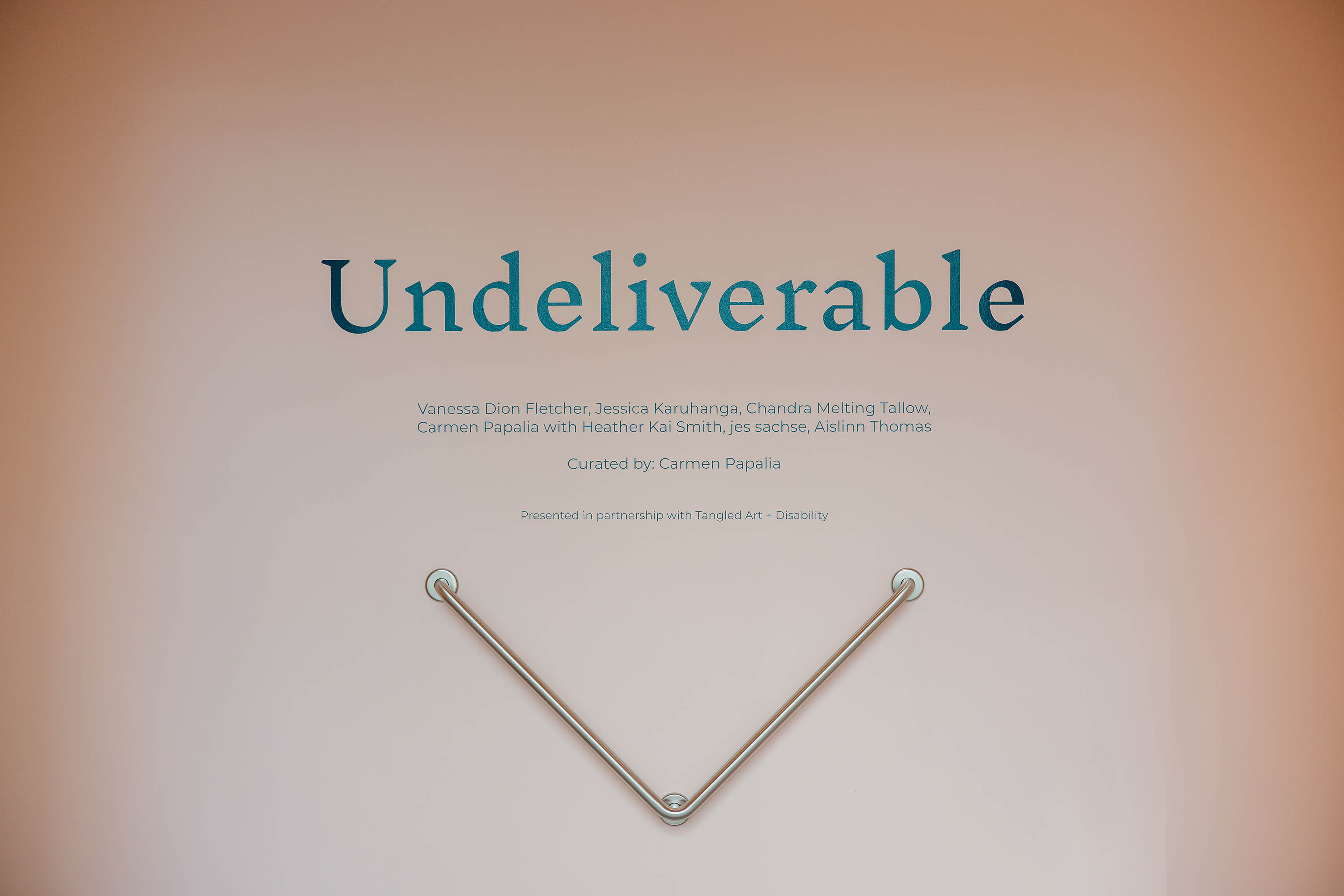 A wall with text that reads “Undeliverable” above a V-shaped grab-bar.