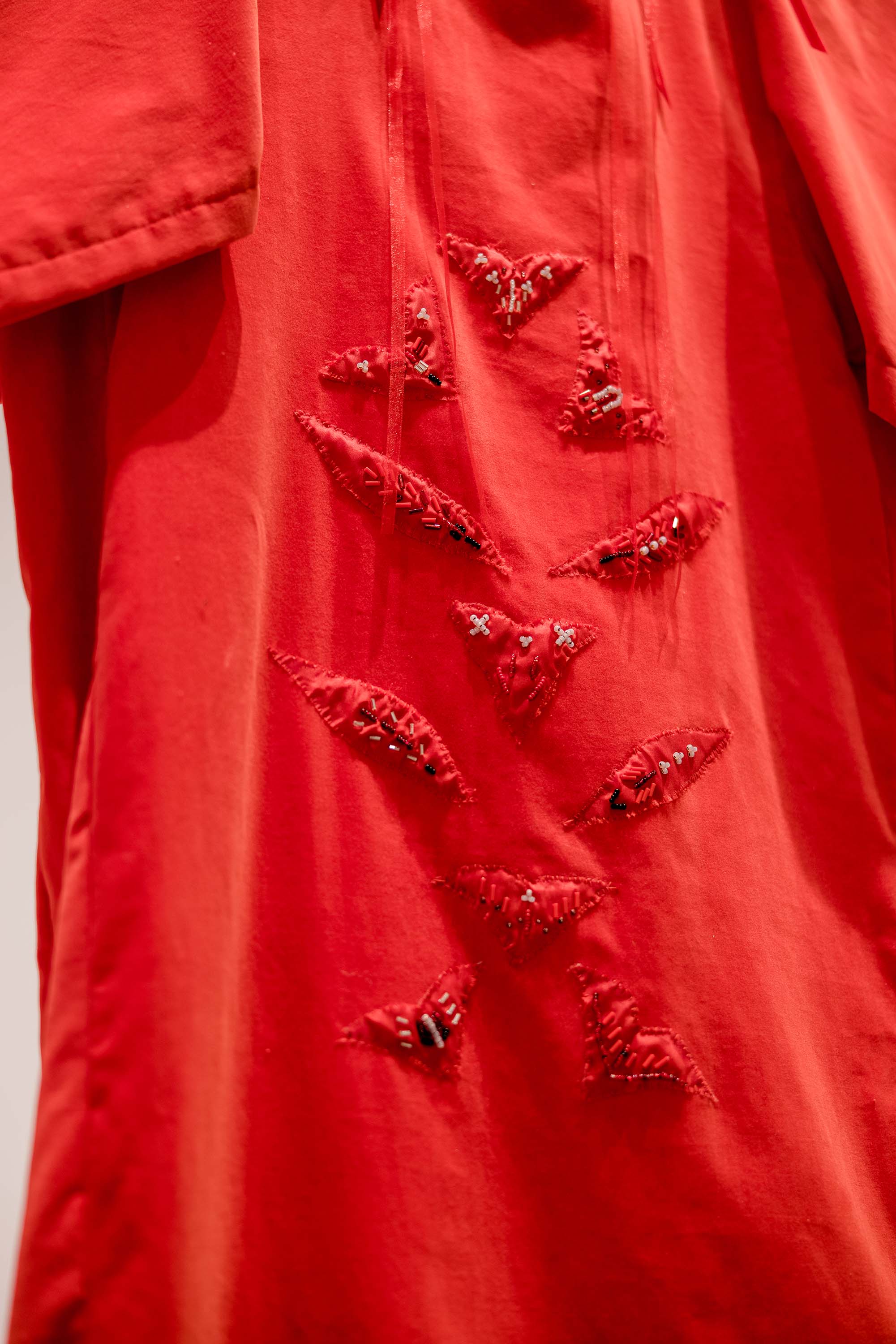 A close-up of a red dress with several beaded red appliques.