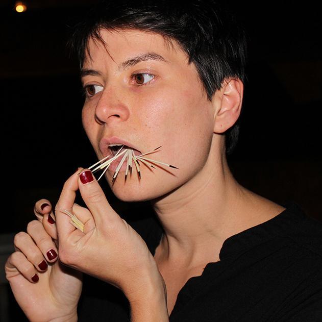 Portrait of Vanessa Dion Fletcher with porcupine quills in her mouth.